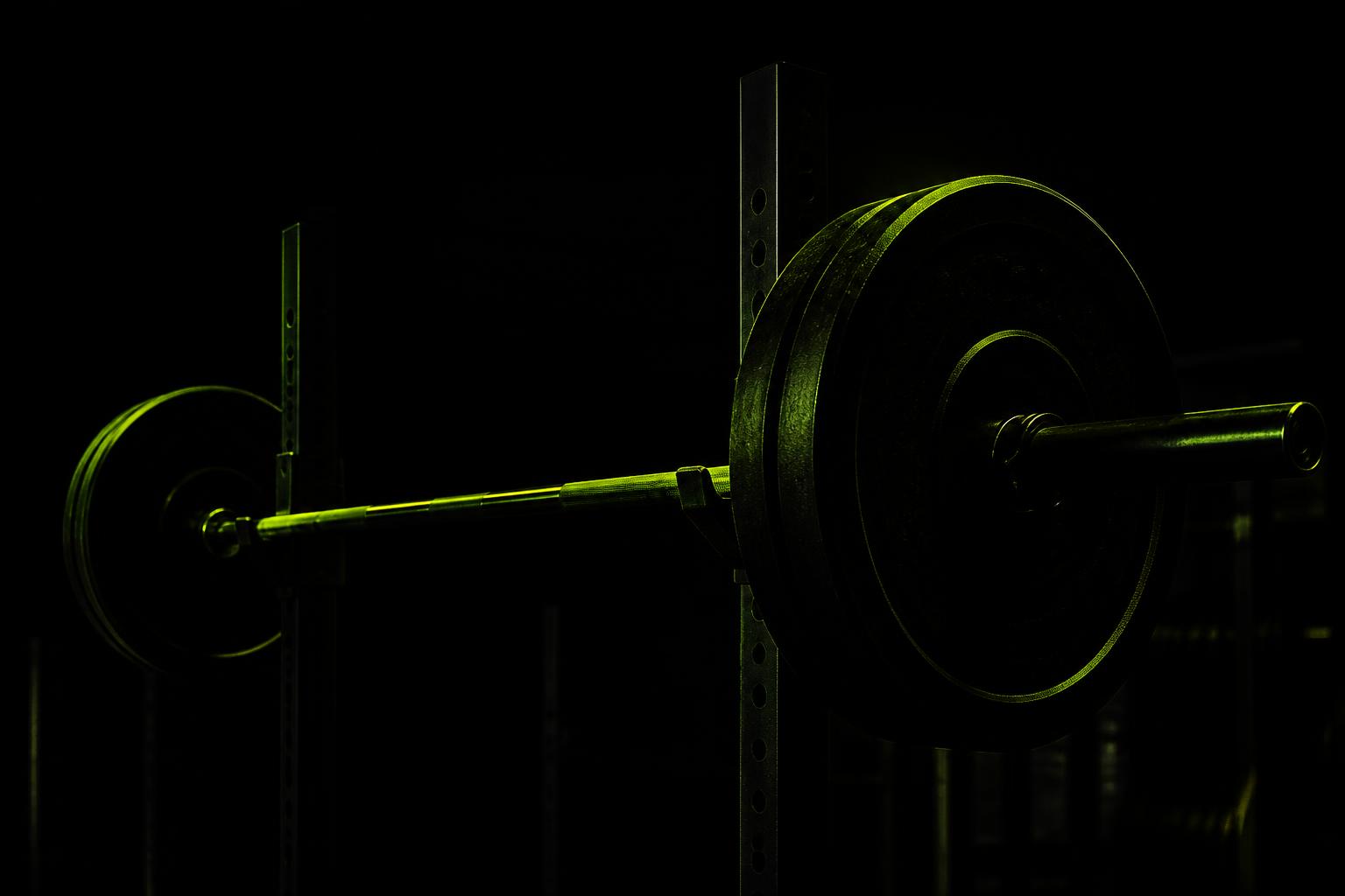 Barbell loaded on a rack in a dark gym lit with green light